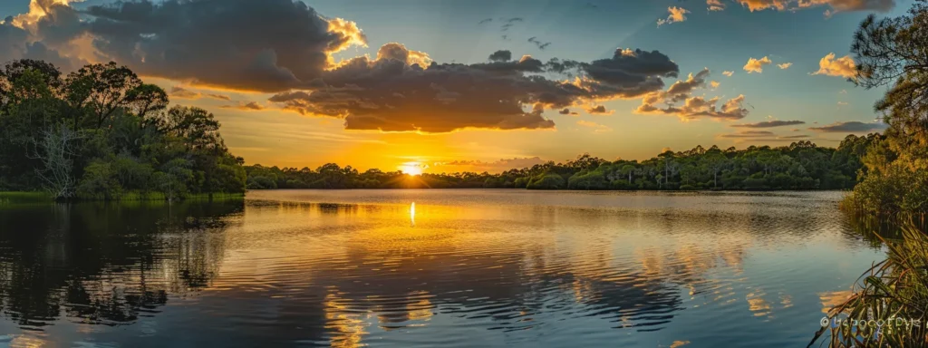 a breathtaking sunset casts a warm golden glow over a tranquil lake, reflecting the vibrant hues of the sky while surrounded by lush greenery, evoking a sense of peace and serenity.